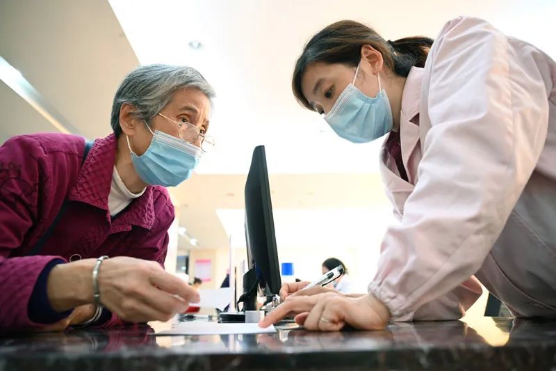 福建省三明市第一医院的医保办工作人员（右）向前来咨询药品报销问题的居民讲解相关政策（2020年11月18日摄）。